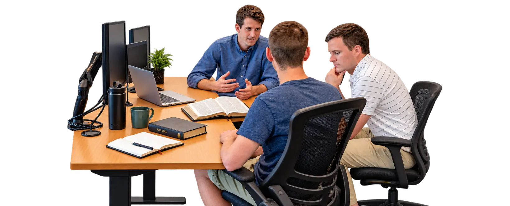 Three coworkers talking over an open Bible at an office desk